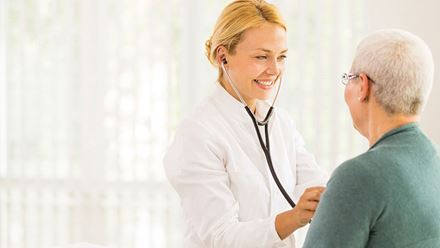 female doctor listening to senior male patient's heart