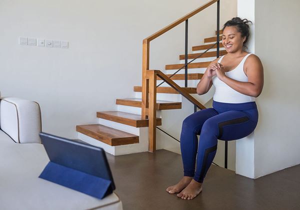 Woman practicing squats against a wall at home