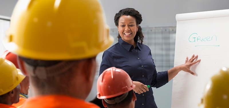 workplace lesson with people in hard hats and teacher at white board