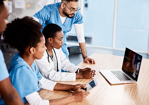 group of medical professionals looking at a laptop