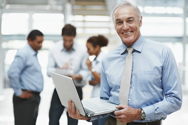 man in business office environment holding laptop