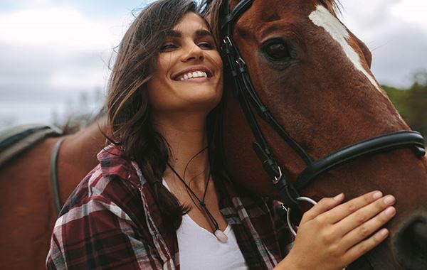 smiling woman hugs horse