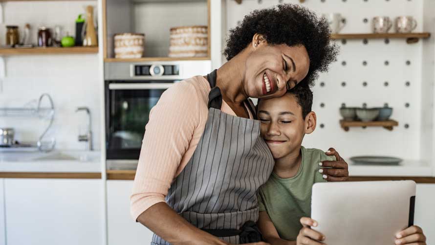 Young boy and his mother hugging him in the kitchen